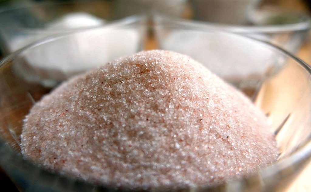 Verschillende soorten natuurzouten in biologische voeding, inclusief himalayazout en zeezout met hun karakteristieke kleuren